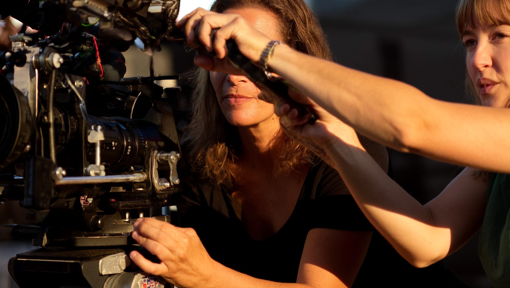 Two crew members carefully steadying and adjusting a camera rig together on a film set