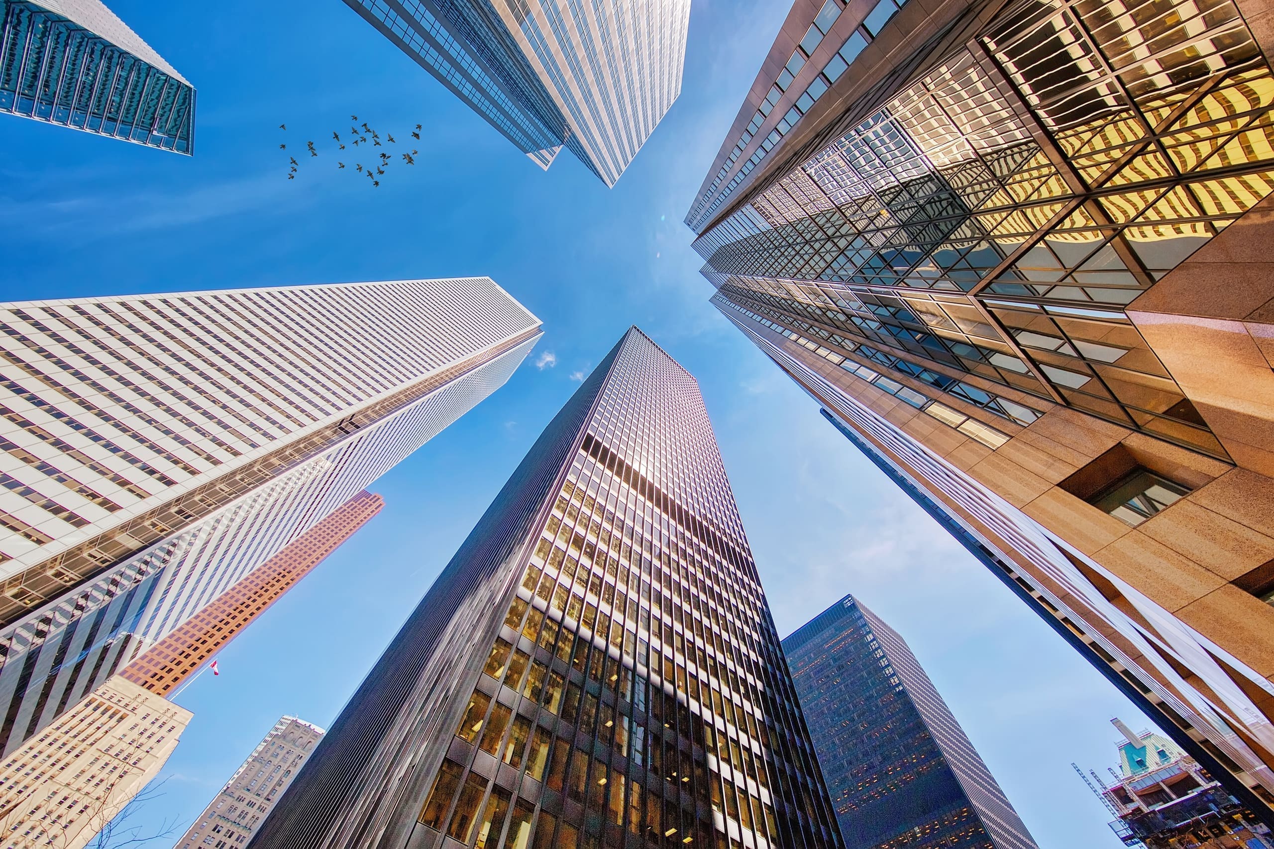 Looking up at glass office towers against a blue sky
