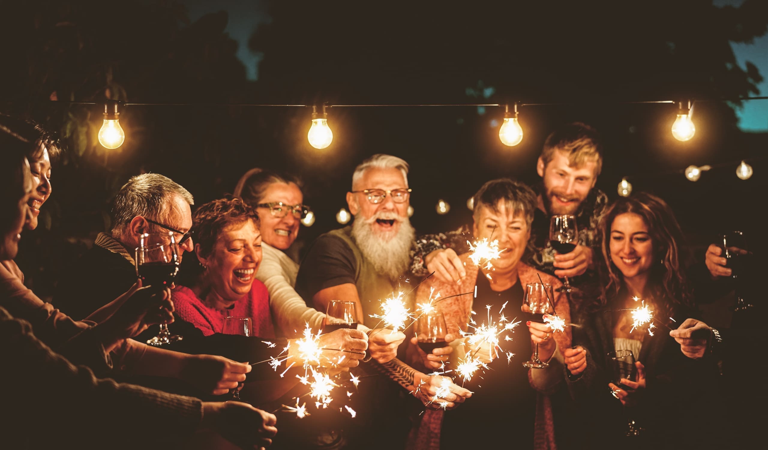 Guests celebrating with sparklers and wine at an outdoor evening party