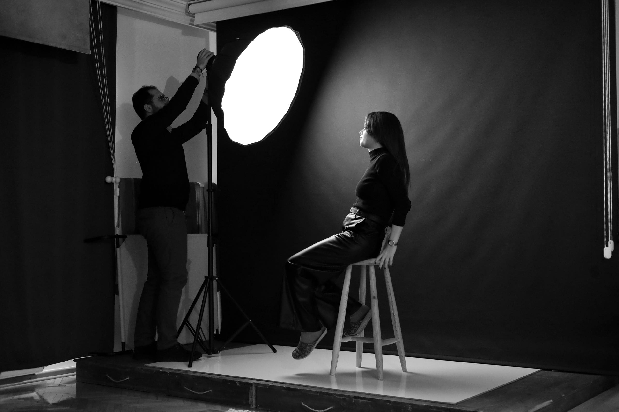 Photographer directing a subject during a studio portrait session against a seamless backdrop