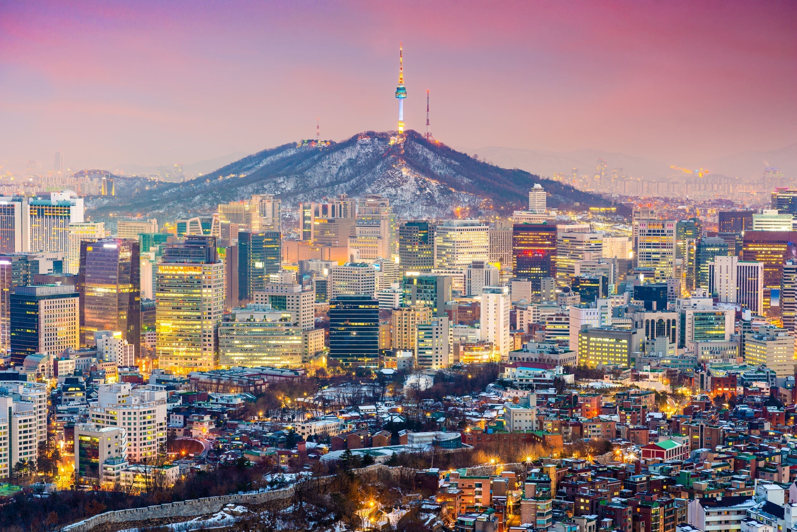 City skyline at twilight with a broadcast tower on the mountain